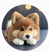 A cute, plush toy resembling a Corgi, with soft fur, big eyes, and a curled tail, resting on a blurred background with warm lights.